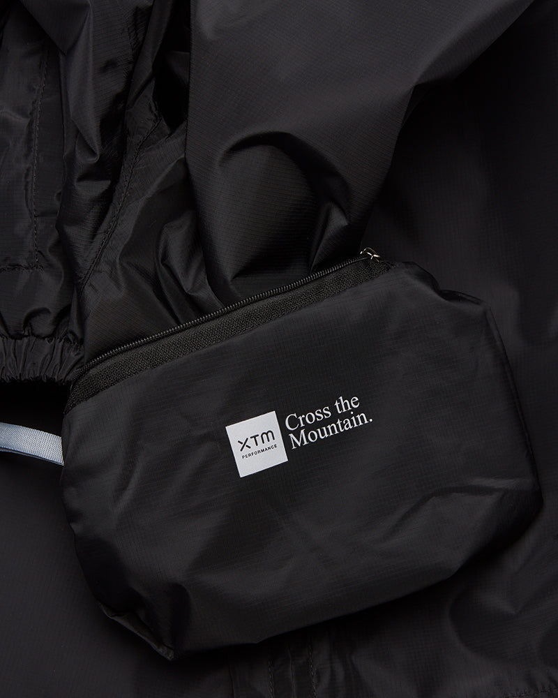 XTM Kids Stash 2L rain pant packed into its zip pocket, with the XTM Cross the Mountain label