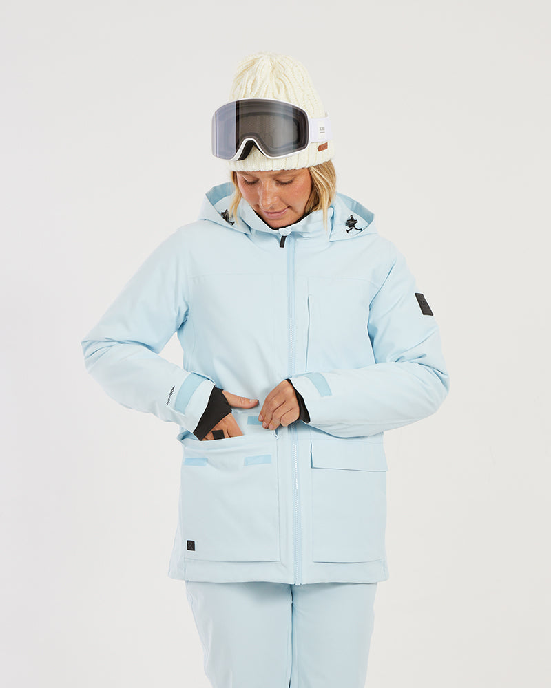 Close-up of a woman reaching into the front of the Sky Blue XTM Elevation II, thumb-hole cuff visible