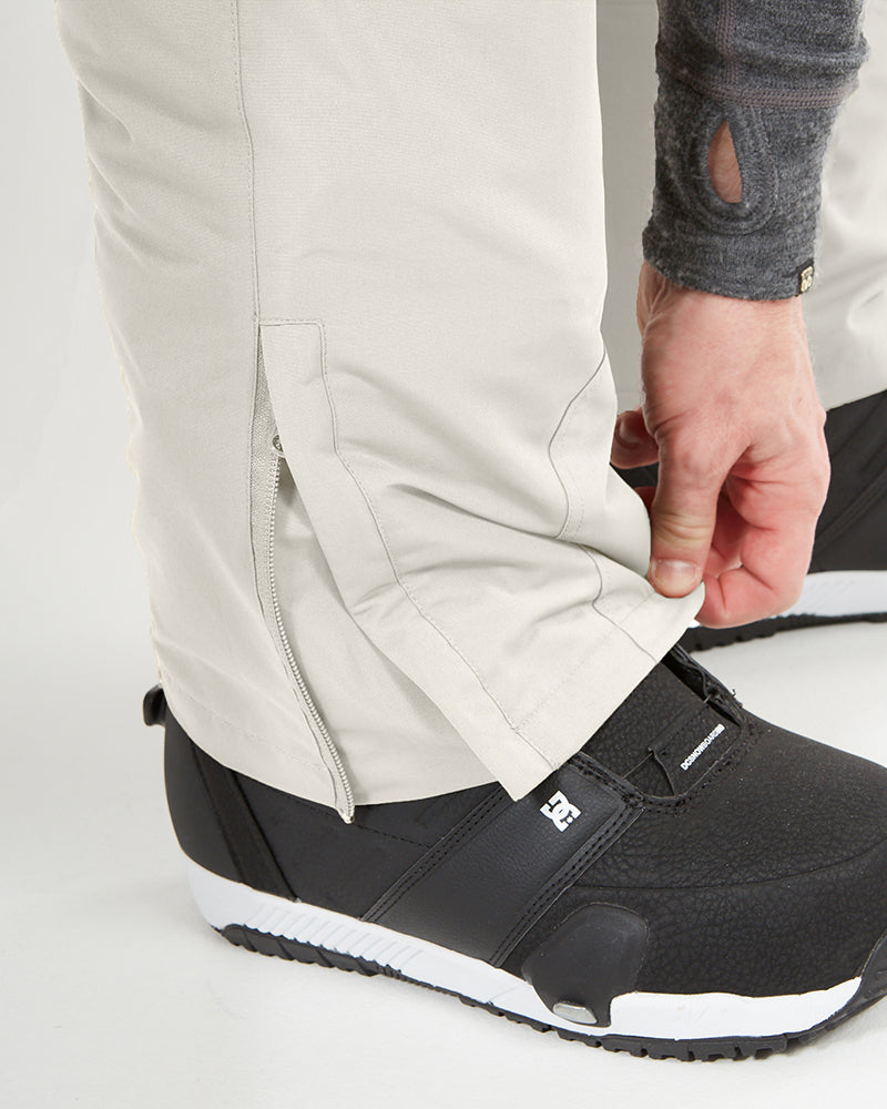 Stone Grey XTM Glide ski pant cuff lifted over a snowboard boot