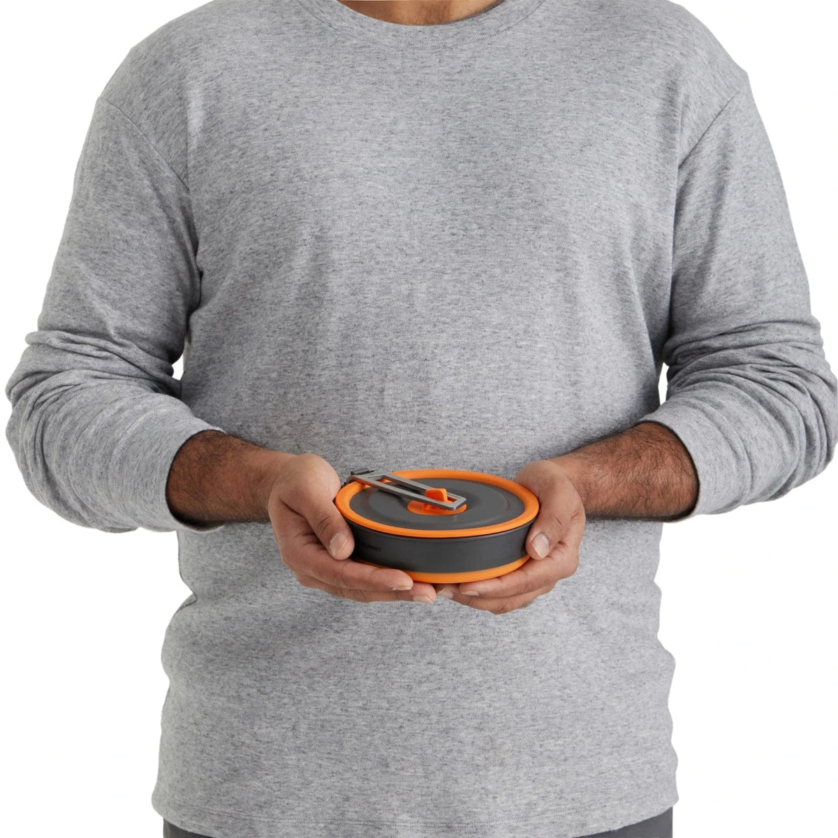 Man holding the Frontier UL One Pot Cook Set collapsed flat with the handle locked over the lid