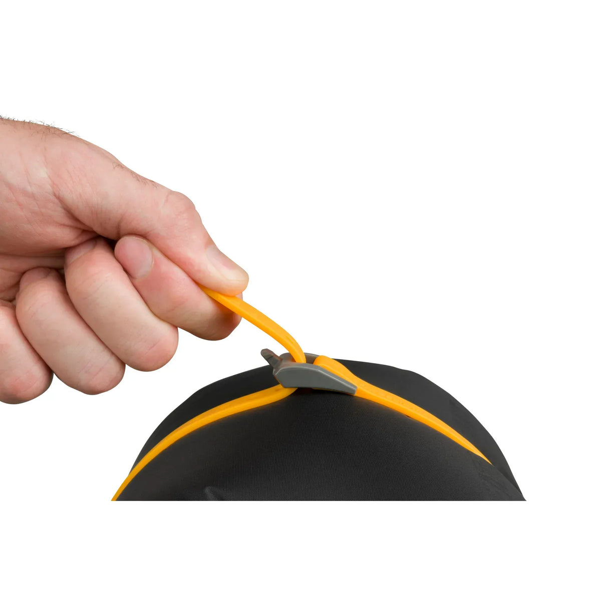 Hand tensioning a yellow Stretch-Loc strap over a black stuff sack