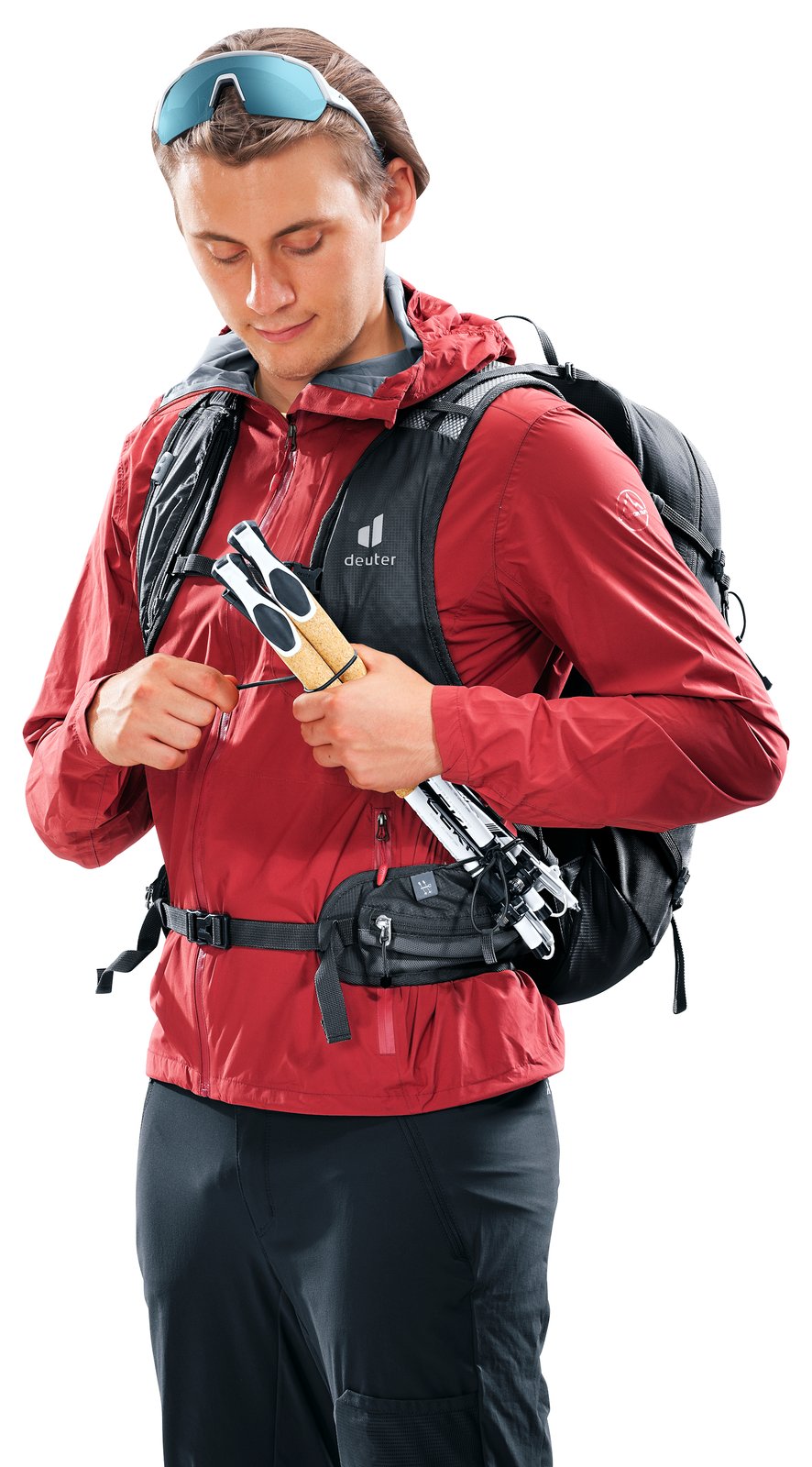 Hiker sliding folded poles into the quick-release holders on the Deuter Speed Lite Pro 25 straps