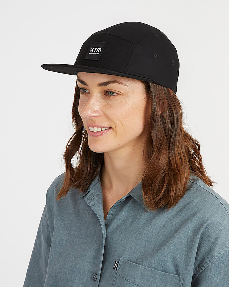 Woman wearing the black XTM Hakea organic cotton cap, three-quarter view