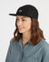 Woman wearing the black XTM Hakea organic cotton cap, three-quarter view