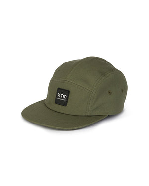 XTM Hakea 5-panel cap in Thyme, three-quarter view showing flat peak and black XTM logo patch