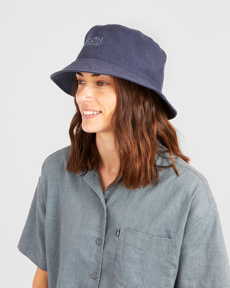 Woman wearing the XTM Sundew bucket hat in Indigo navy, side view with the eyelet vent