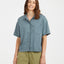 Woman in the Basalt blue-grey XTM Tea Tree hemp-blend short sleeve shirt, front view with chest pocket
