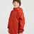 Boy in the XTM Kids Stash 2L packable rain jacket in Burnt Orange, three-quarter front view