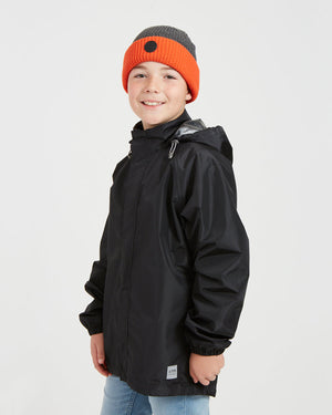 Boy in the XTM Kids Stash 2L rain jacket in Black, angled view showing the side pocket