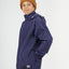 Boy in the XTM Kids Stash 2L rain jacket in Patriot Blue, hand in a side zip pocket