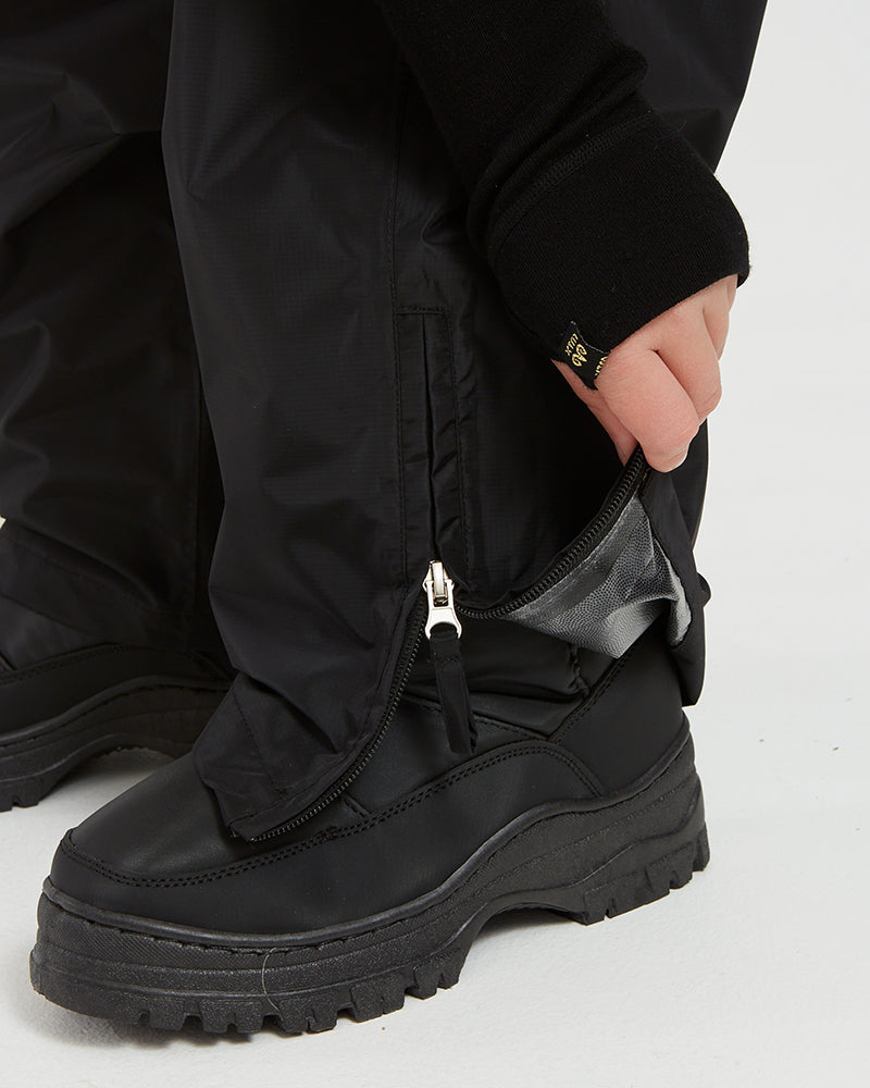 Lower leg zip open over a boot on the XTM Kids Stash 2L rain pant in Black