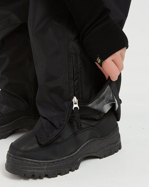 Lower leg zip open over a boot on the XTM Kids Stash 2L rain pant in Black