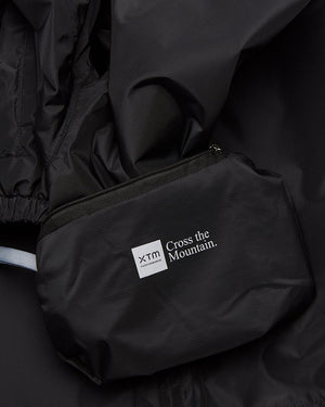 XTM Kids Stash 2L rain pant packed into its zip pocket, with the XTM Cross the Mountain label