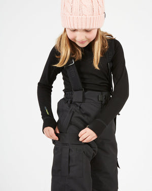 XTM Kids Pluto II Snow Pant in Black, child opening the thigh pocket