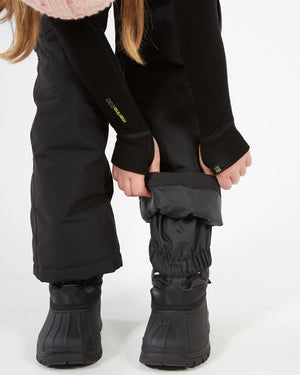 XTM Kids Pluto II Snow Pant in Black, close-up of the elasticised boot gaiter over a snow boot