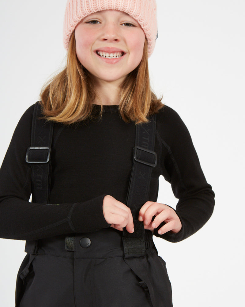 XTM Kids Pluto II Snow Pant in Black, child adjusting a brace at the waist