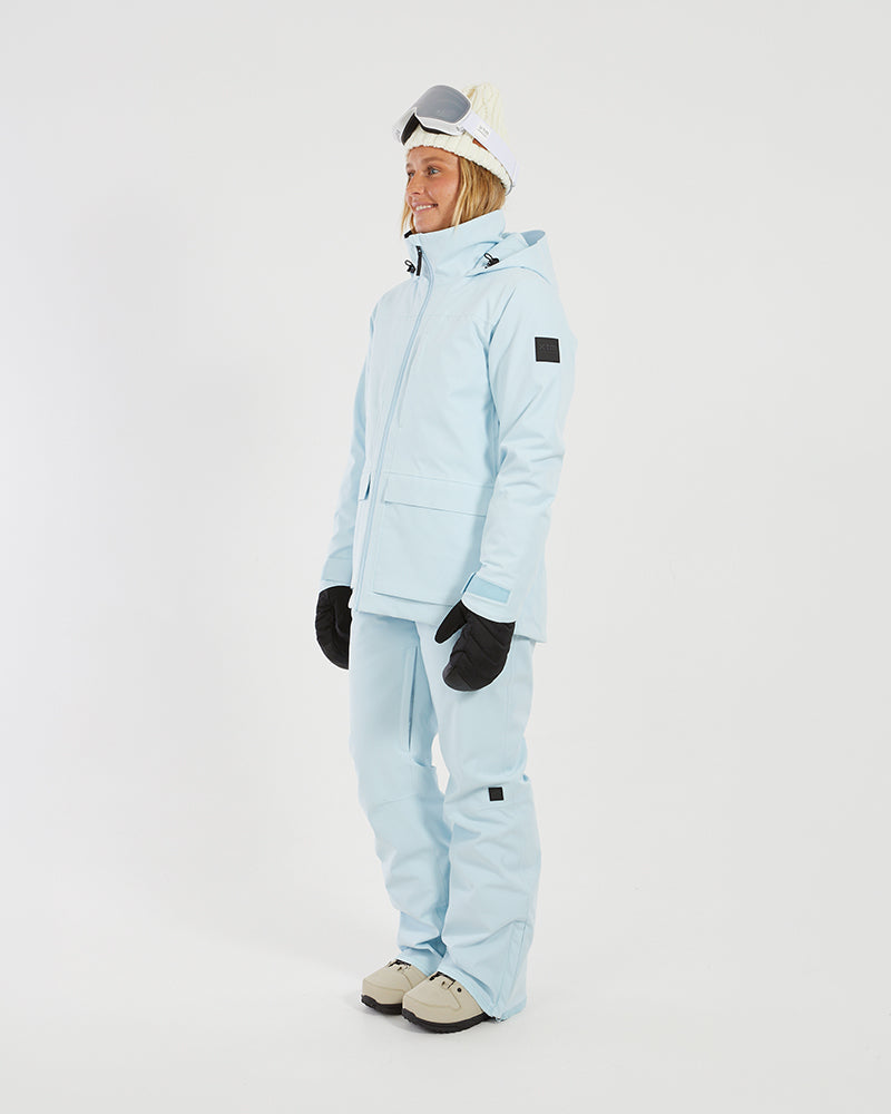 Side view of a woman in the Sky Blue XTM Elevation II jacket showing the sleeve badge