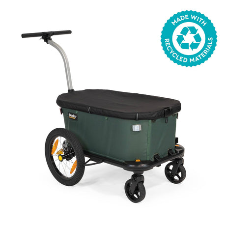 Burley Hopper in wagon mode, green body with black cover, pull handle and caster wheels, recycled materials badge