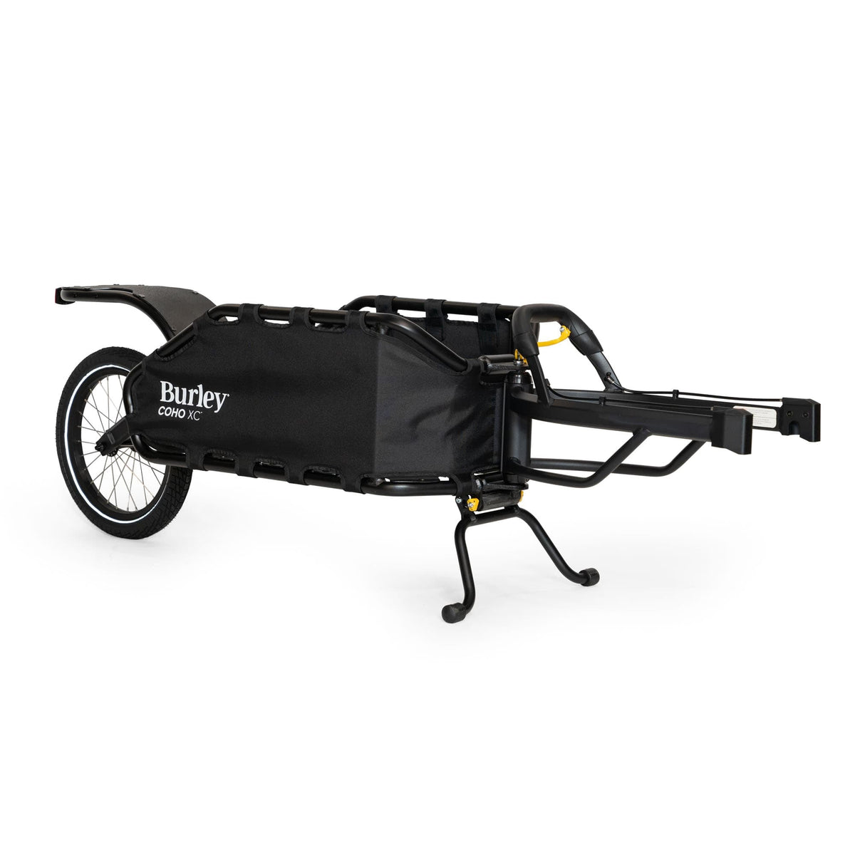 Burley Coho XC single-wheel cargo trailer in black, standing on its kickstand, tow arm to the right