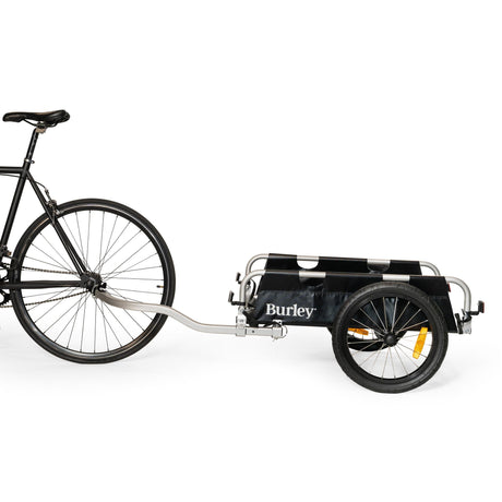 Burley Flatbed hitched to the rear axle of a black bike, side view showing the tow arm
