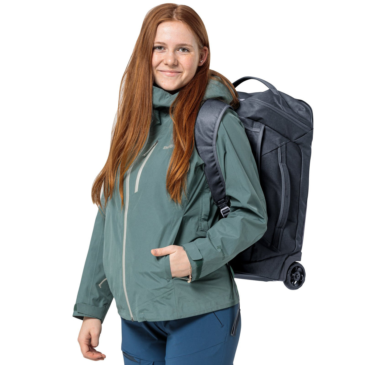 Traveller in a green rain jacket carrying the Deuter Duffel Pro Movo 36 as a backpack