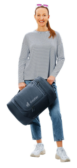 Woman carrying the Deuter Duffel Pro Pack 30 in Black by its padded grab handles