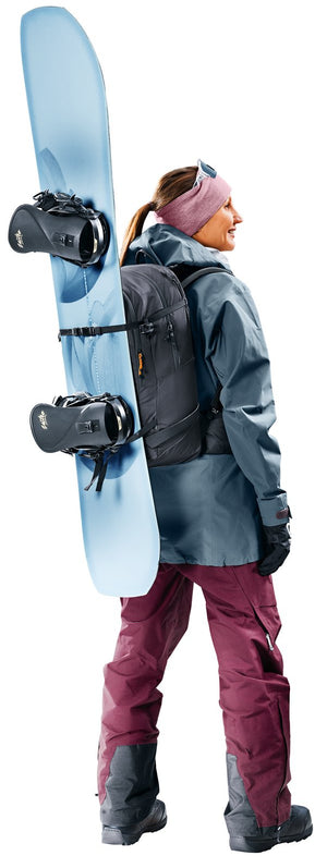Woman wearing the Deuter Freerider 28 SL with a snowboard strapped to the front