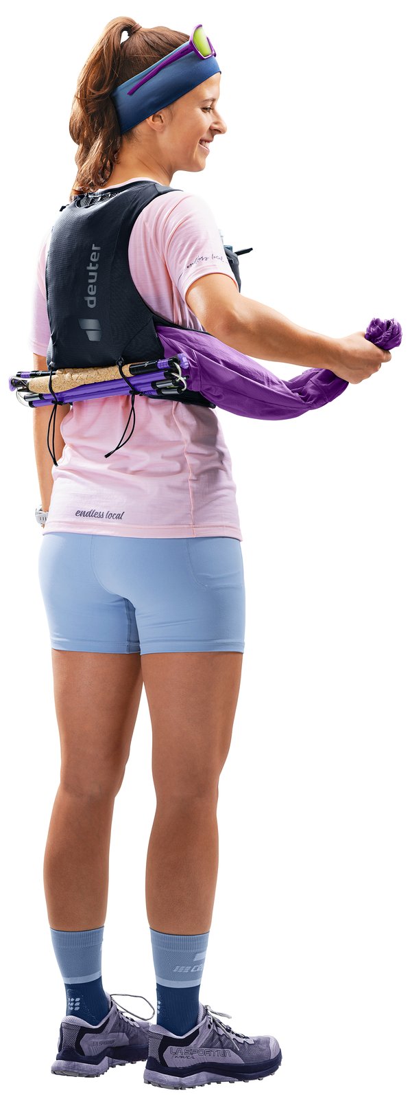 Runner wearing the Deuter Traick 5 SL with poles stowed across the back, side view