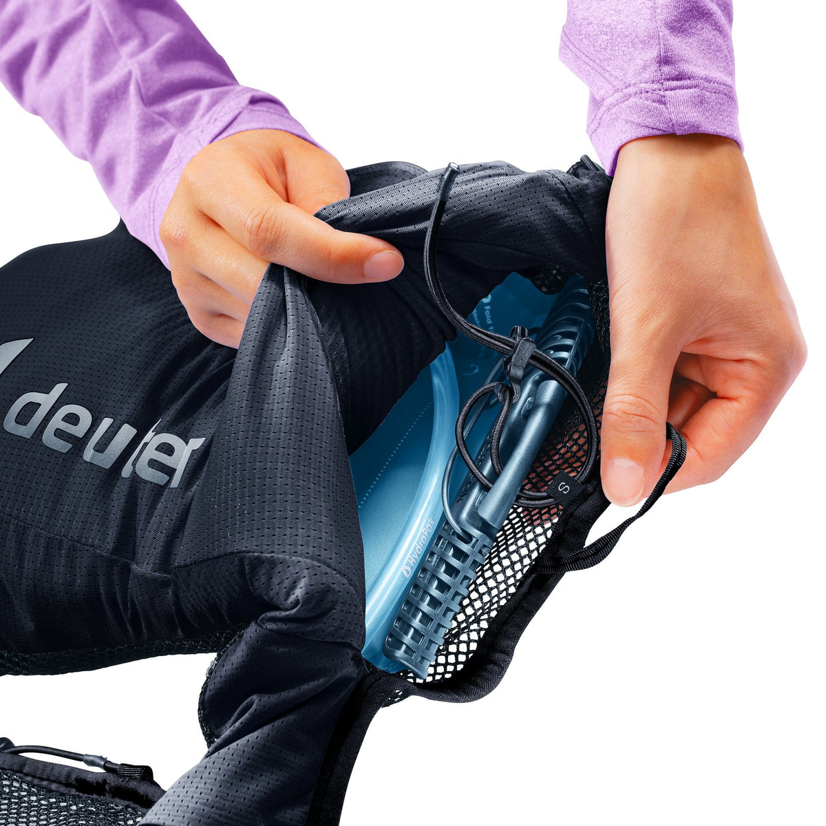 Hands sliding a hydration bladder into the back sleeve of the Deuter Traick 9 SL