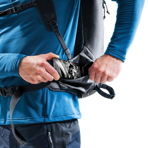 Skier reaching into the bottom compartment of the Deuter Updays 26 while wearing it